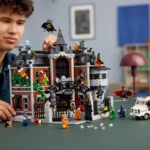 Junge spielt mit einem detaillierten LEGO-Set des Arkham Asylums, das mehrere Batman-Figuren und ein weißes Fahrzeug mit Polizeilichtern zeigt.