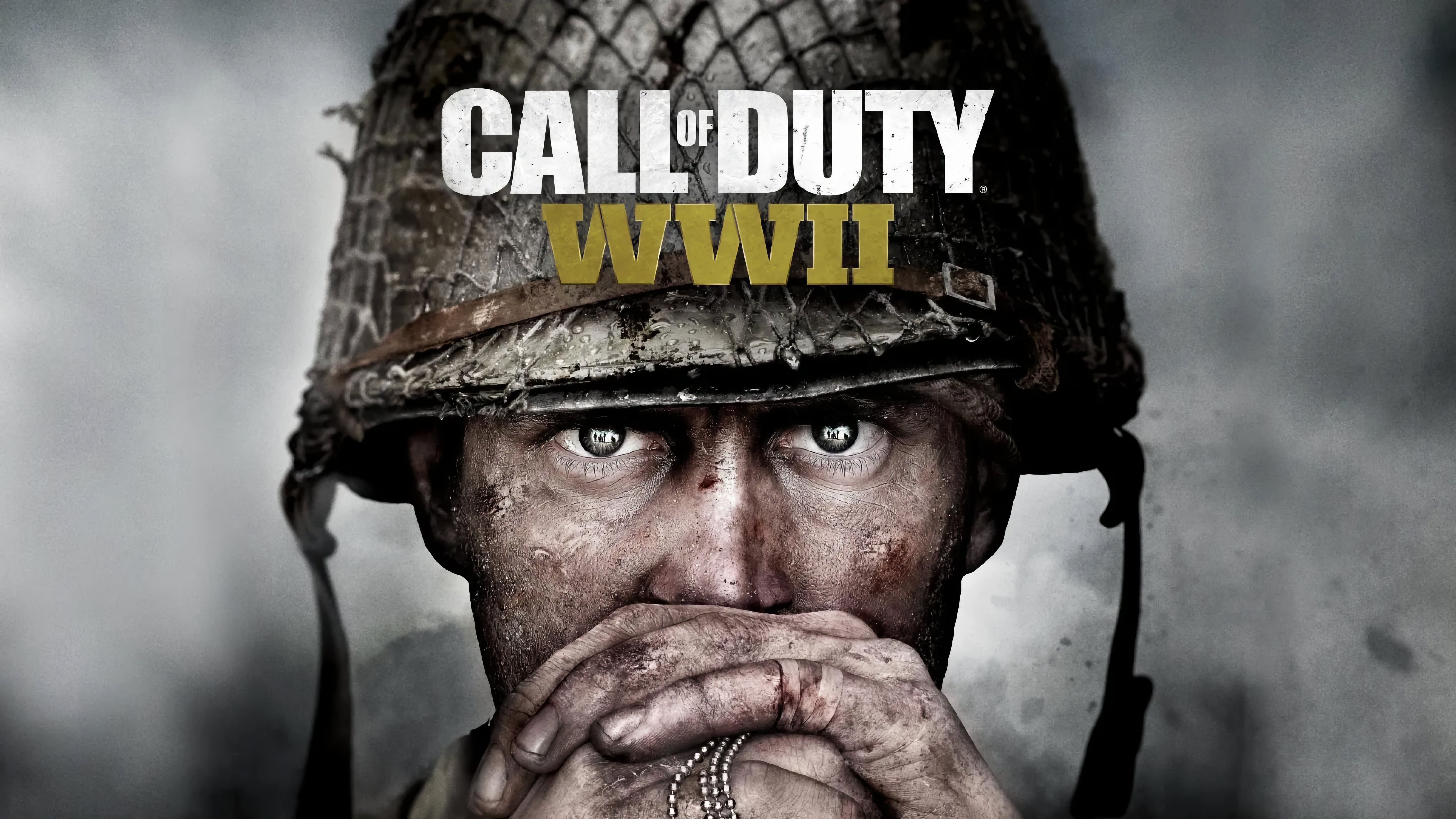 Nahaufnahme eines Soldaten mit schmutzigem Gesicht und Händen, der einen abgenutzten Stahlhelm trägt und die Hände vor den Mund hält. Im Hintergrund ist der Schriftzug „CALL OF DUTY WWII“ zu sehen.